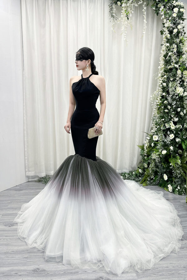 Black halter mermaid gown with gradient tulle skirt (black to white) and sweeping train, styled with a lace mask and beaded clutch.