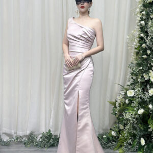 Stunning blush pink one-shoulder satin mermaid gown with ruched bodice, high thigh slit, and trailing train, styled with a lace mask and beaded clutch.