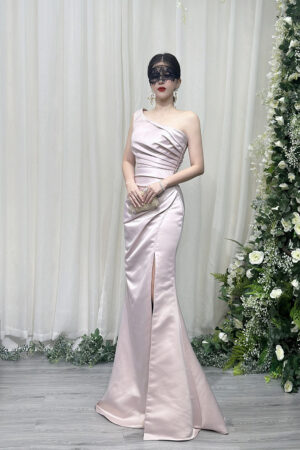Stunning blush pink one-shoulder satin mermaid gown with ruched bodice, high thigh slit, and trailing train, styled with a lace mask and beaded clutch.