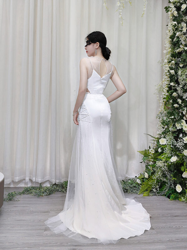 Elegant white tulle mermaid evening dress with sheer neckline, side cutouts, and crystal embellishments.