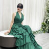Glamorous emerald green halter-neck tiered gown with glittery ruffle layers and dramatic trailing train.