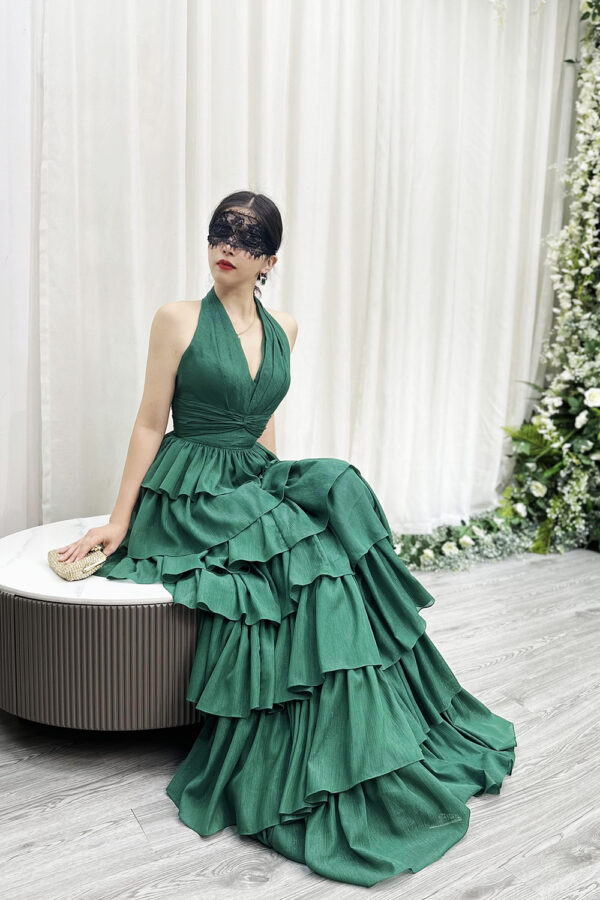 Glamorous emerald green halter-neck tiered gown with glittery ruffle layers and dramatic trailing train.