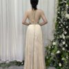 Luxury champagne gold pleated halter gown with crystal-embellished waistband and flowing skirt.