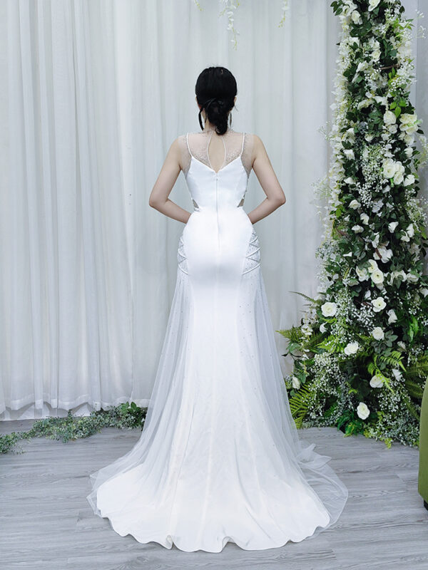 Luxury white crystal-embellished mermaid gown with sheer neckline and side mesh cutouts.