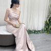 Modern blush pink one-shoulder satin gown with ruched bodice, high slit, and trailing train.