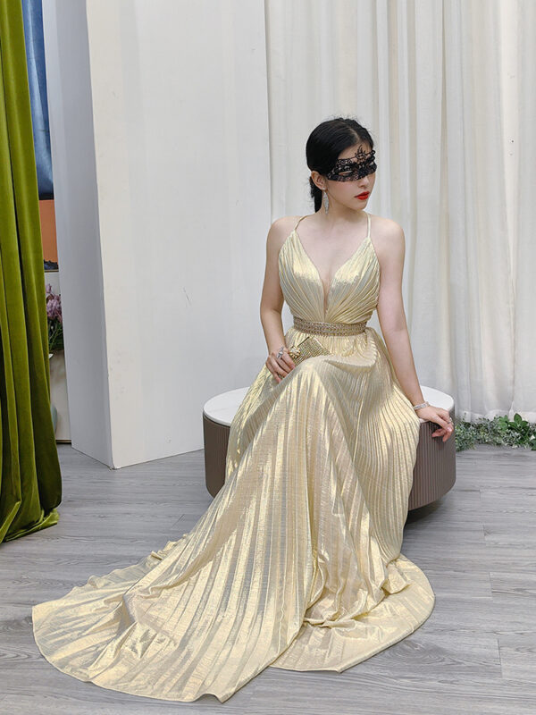 Modern champagne metallic pleated gown with halter straps, deep V plunge, and beaded waistband.