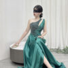 Modern emerald green one-shoulder satin gown with beaded detailing, high slit, and trailing train.