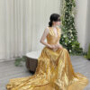 Modern gold metallic pleated gown with deep V-neck, ruched waist, high slit, and sweeping train, styled with a lace mask and beaded clutch.