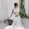Modern white mermaid gown with sheer beaded bodice, spaghetti straps, and satin skirt with twisted waist detail.