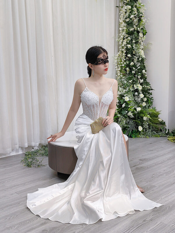 Modern white mermaid gown with sheer beaded bodice, spaghetti straps, and satin skirt with twisted waist detail.