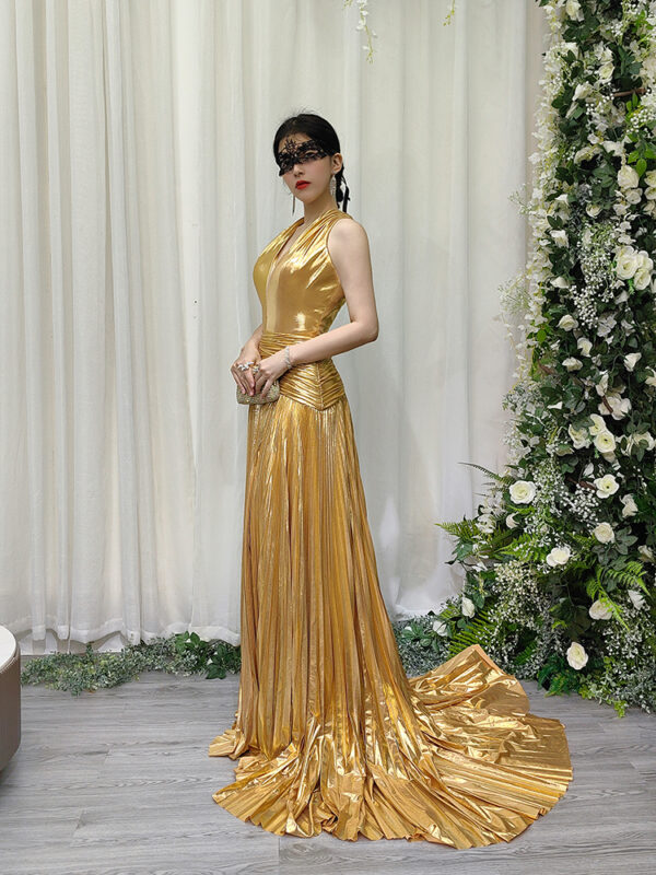 Opulent gold metallic pleated gown with deep plunge neckline, high side slit, and floor-sweeping train.