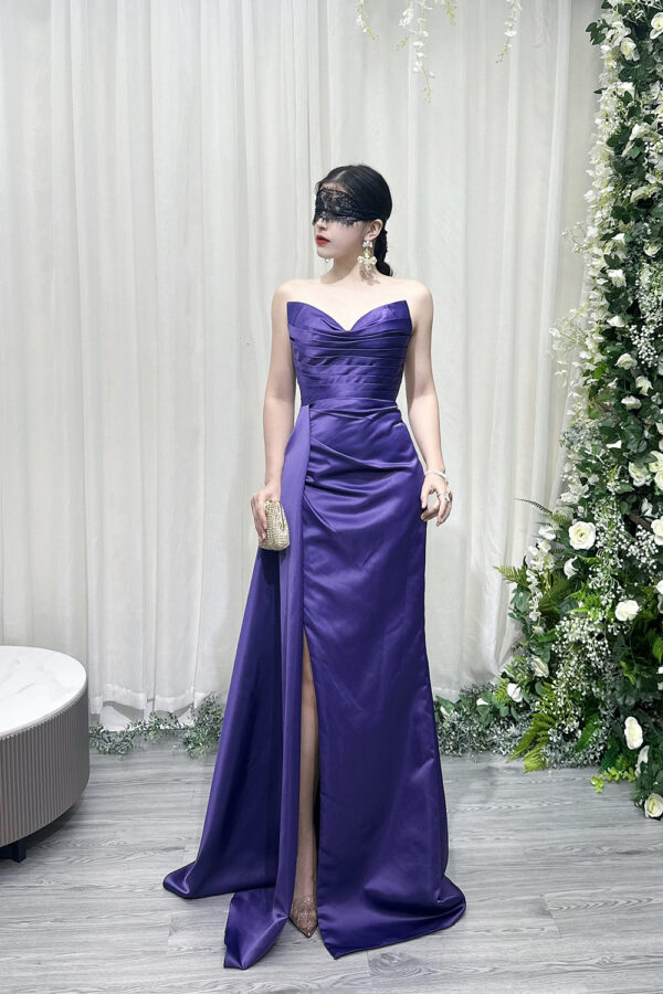 Stunning purple strapless satin mermaid gown with ruched bodice, high slit, and trailing train, styled with a lace mask and beaded clutch.