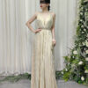 Romantic champagne pleated halter gown with deep V-neck and beaded waist, styled with a lace mask and beaded clutch.
