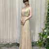 Elegant champagne metallic pleated dress with halter straps, deep V-neck, and beaded waist detail.