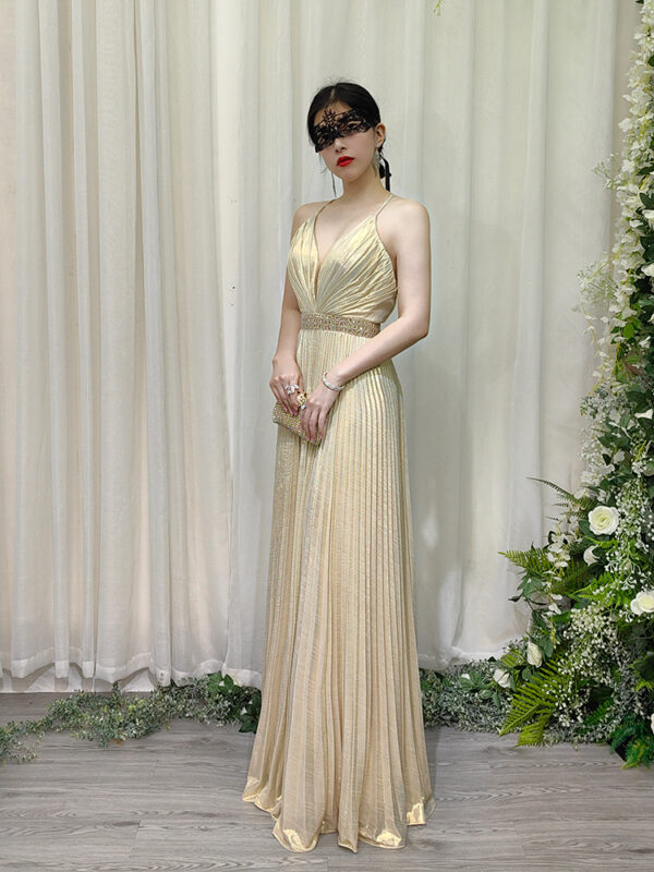 Elegant champagne metallic pleated dress with halter straps, deep V-neck, and beaded waist detail.