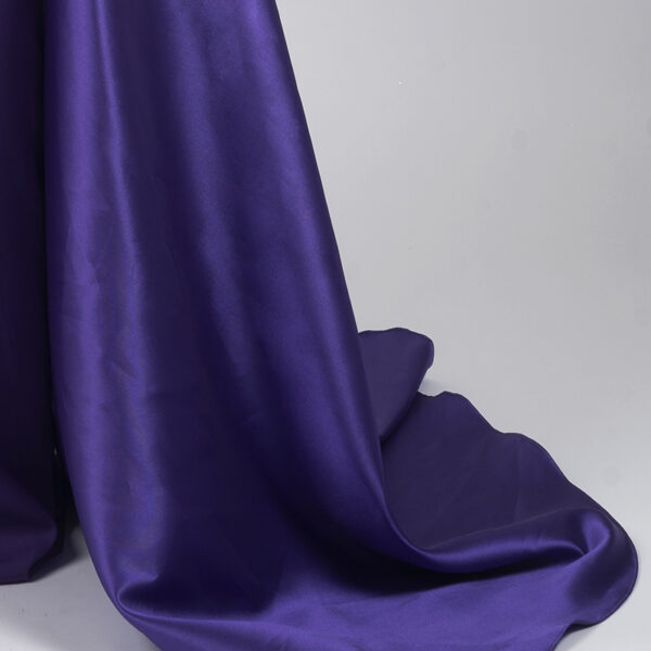 Dramatic deep purple off-the-shoulder satin floor-length gown with corset waist and flowing side train, red-carpet worthy formal wear.