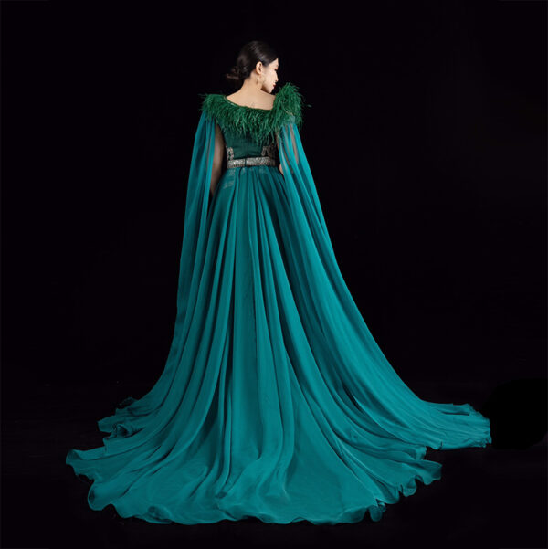 Regal emerald green mermaid gown with feathered neckline, silver beaded waist, and sheer chiffon cape train, bridal or gala formal wear