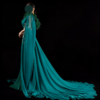 Dramatic emerald green mermaid evening gown with feather trim, beaded bodice, and sheer chiffon cape, perfect for black-tie events